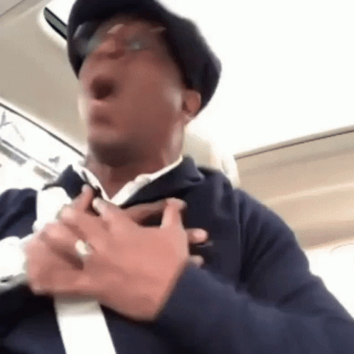 Man With Hat and Glasses Holding Chest in Car