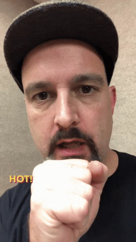 Man With Hat and Mustache Holding Fist Up Saying Hot