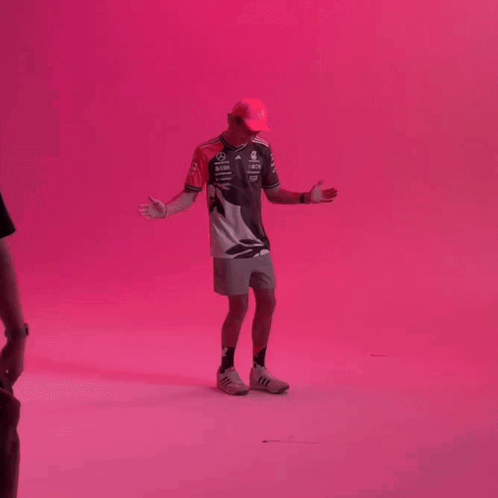Man With Hat Arms Outstretched Pink Wall