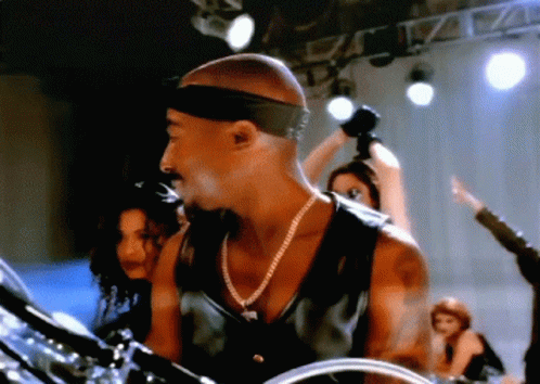 Man With Headband And Necklace Playing Drums On Stage GIF