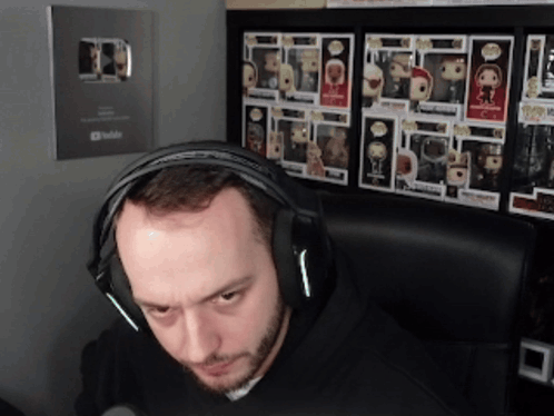 Man With Headphones In Front Of Funko Pop Wall GIF