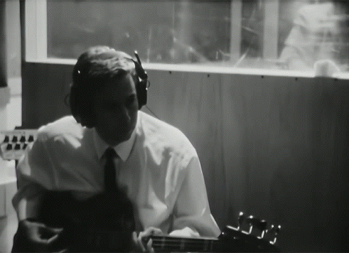 Man with Headphones Playing Guitar in Dark Room