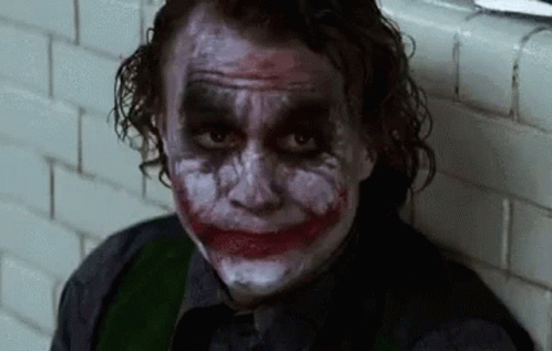 Man with Joker Makeup Sitting Next to Wall