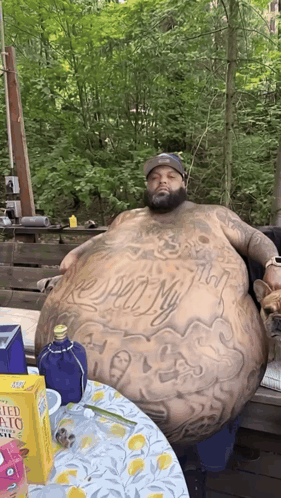 Man With Large Belly Sitting at Table With Potato Chips