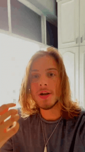 Man With Long Blonde Hair and Beard in Grey Shirt and Silver Necklace