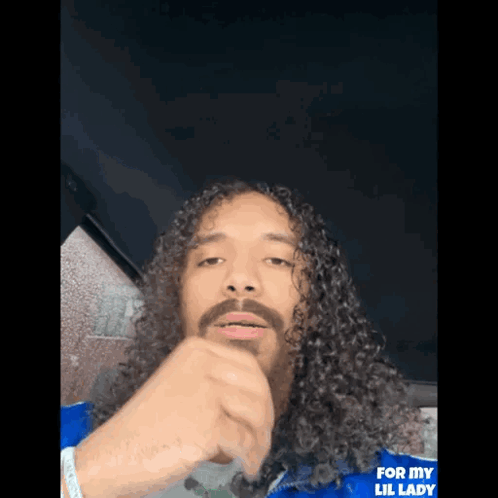 Man with Long Curly Hair and Beard in Blue Jacket Saying For My Lil Lady
