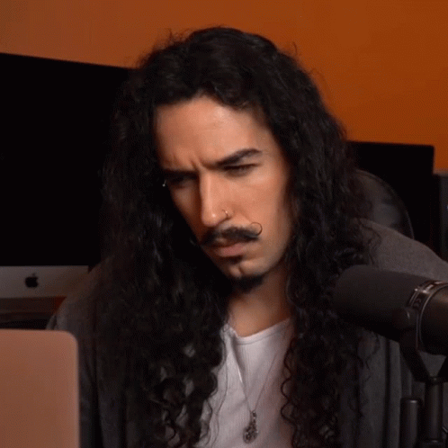 Man With Long Curly Hair and Beard Looking at Laptop