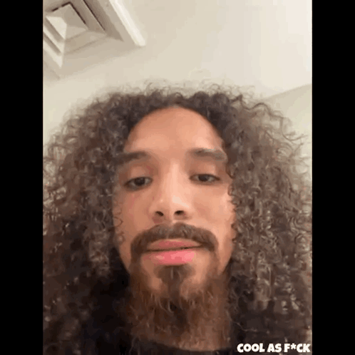 Man with Long Curly Hair and Beard Making Funny Face