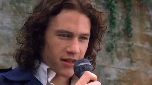 Man With Long Curly Hair Singing Into Microphone