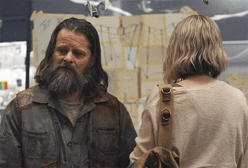 Man With Long Hair and Beard Stands Next to Woman