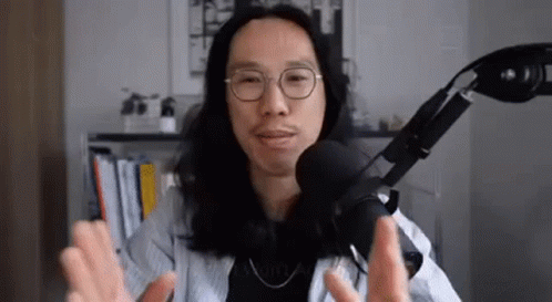 Man With Long Hair And Glasses Talking Into Microphone GIF