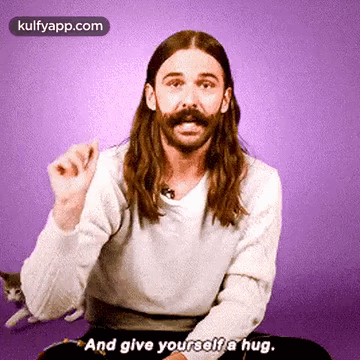 Man With Long Hair and Mustache Hugging Himself