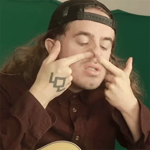 Man With Long Hair And Tattoo Holding Nose GIF