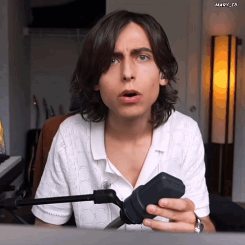 Man with Long Hair Holding Microphone Surprised