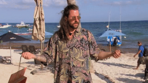 Man With Long Hair on Beach With Boat