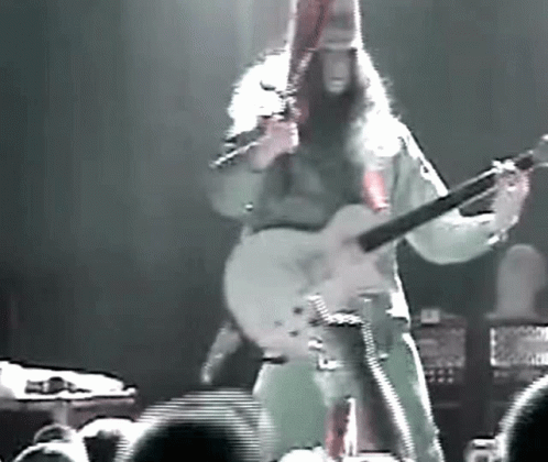 Man With Long Hair Playing Guitar on Stage