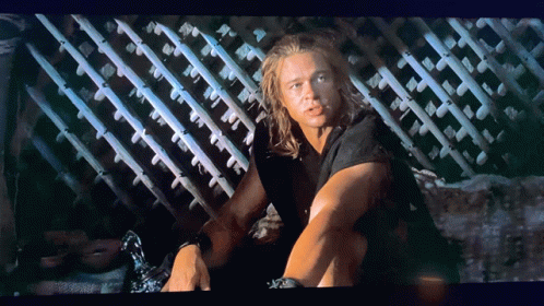 Man With Long Hair Sitting By Fence GIF