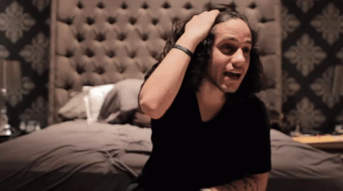 Man With Long Hair Sitting On Bed GIF