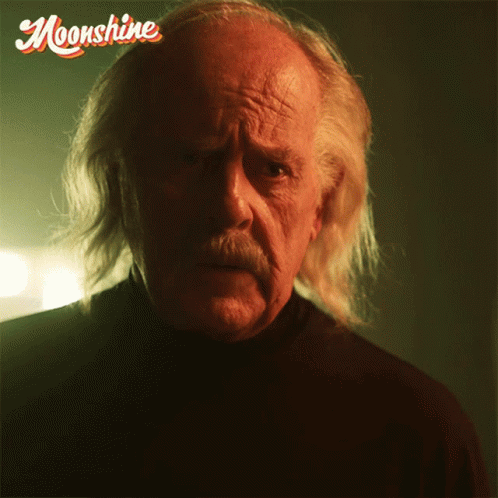 Man with Long White Hair and Mustache Looking at Camera Saying Moonshine