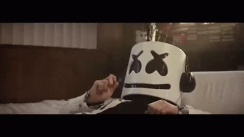 Man With Marshmello Mask And Headphones Lying On Bed GIF