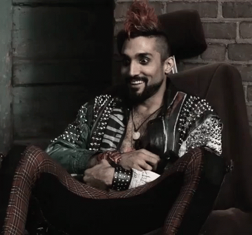 Man with Mohawk Sitting in Chair Wearing Wild Jacket