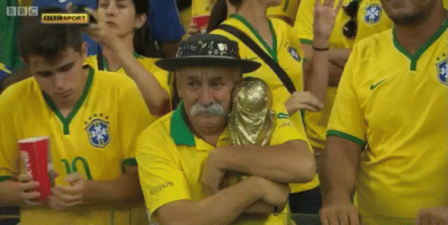 Man With Mustache Holding Trophy In Yellow Jersey Crowd GIF