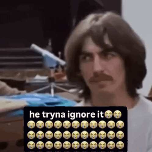 Man With Mustache Sitting in Front of Sign Saying He Tryna Ignore It