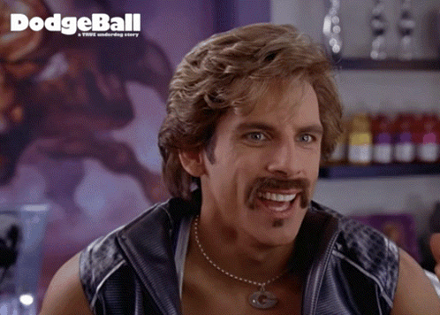 Man With Mustache Smiling In Front of Dodgeball Poster
