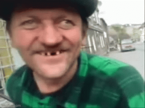 Man With No Teeth In Green Plaid Shirt And Hat Smiling GIF