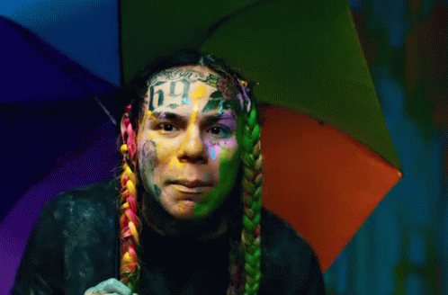 Man With Rainbow Umbrella on Head and Number 6 Face Tattoo