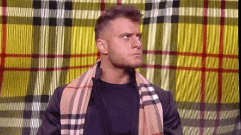 Man With Scarf and Plaid Jacket Before Plaid Curtain