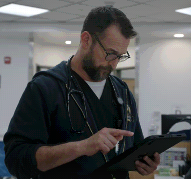 Man With Stethoscope Looking at Tablet