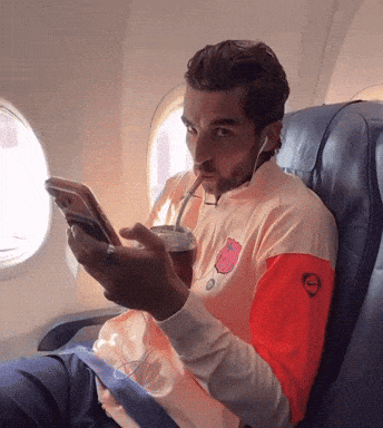 Man with Straw on Airplane Looking at Phone