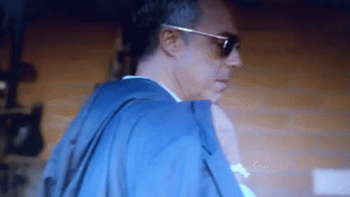 Man With Sunglasses And Blue Jacket In Dark Room GIF