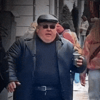Man with Sunglasses and Hat Walking Holding Coffee
