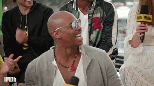 Man with Sunglasses and Necklace Laughing at Imdb Microphone