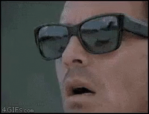 Man with Sunglasses Holding Scissors to Mouth