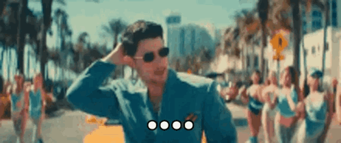 Man With Sunglasses In Blue Jacket Standing In Crowd GIF