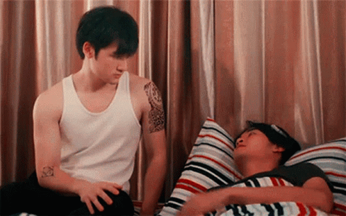 Man With Tattoo Standing Next to Man in Bed