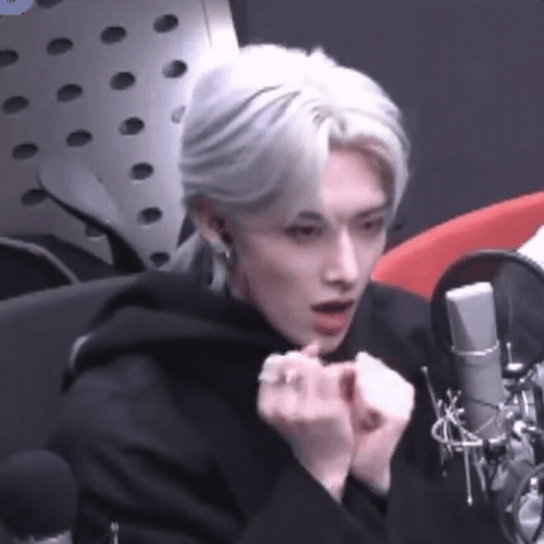 Man With White Hair Sitting at Microphone in Studio