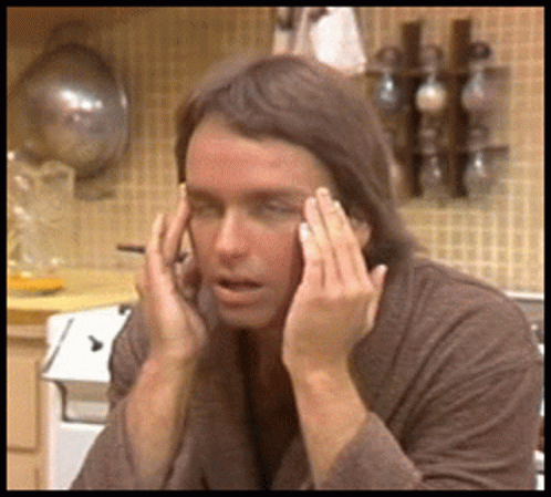 Man With Wig and Sunglasses Watching Man in Headphones