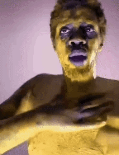 Man With Yellow Paint On Face Holding Hands To Chest GIF
