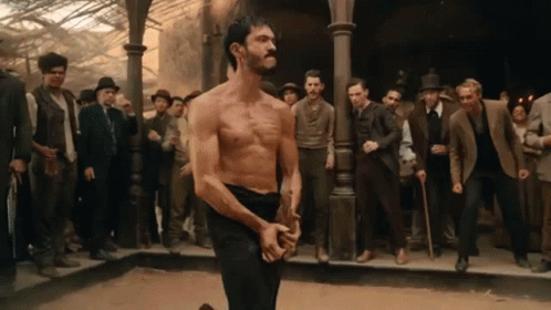 Man Without Shirt Facing Crowd of Men