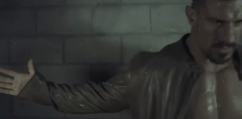 Man Without Shirt in Front of Brick Wall