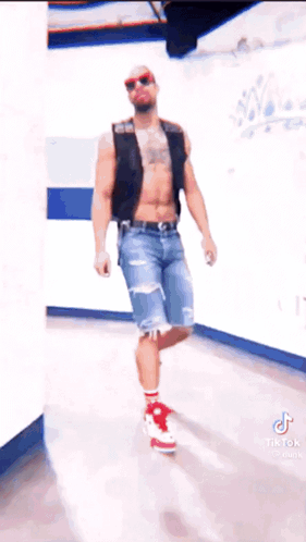 Man Without Shirt in Hallway Wearing Red Shoes and Sunglasses