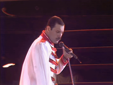 Man Without Shirt Singing into Microphone Holding Flag