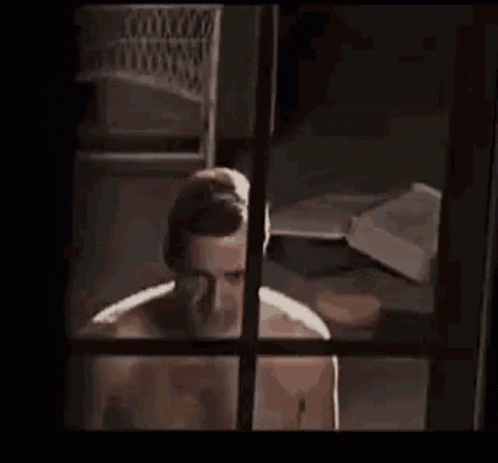 Man Without Shirt Standing By Window GIF