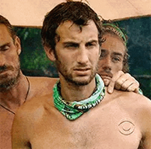 Man Without Shirt Standing Next to Two Men