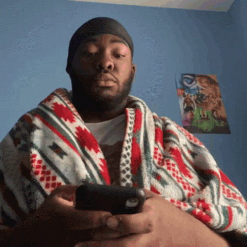 Man Wrapped in Colorful Blanket Looking at Phone