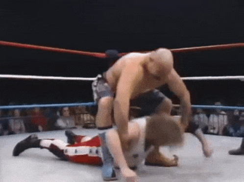Man Wrestling Another Man in Ring With Crowd